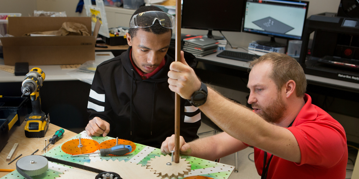 Student and adult mentor work on an engineering project.