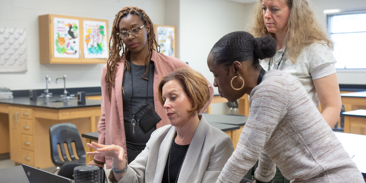 Woman pointing at computer while three others look on