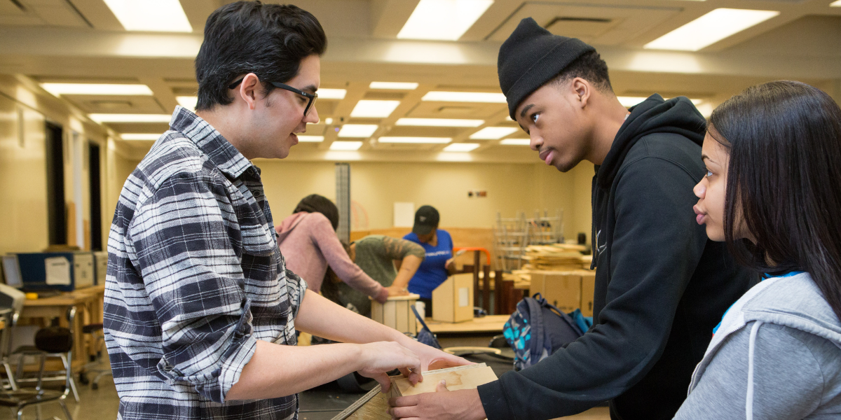 Adult and student work on wood-working project together.