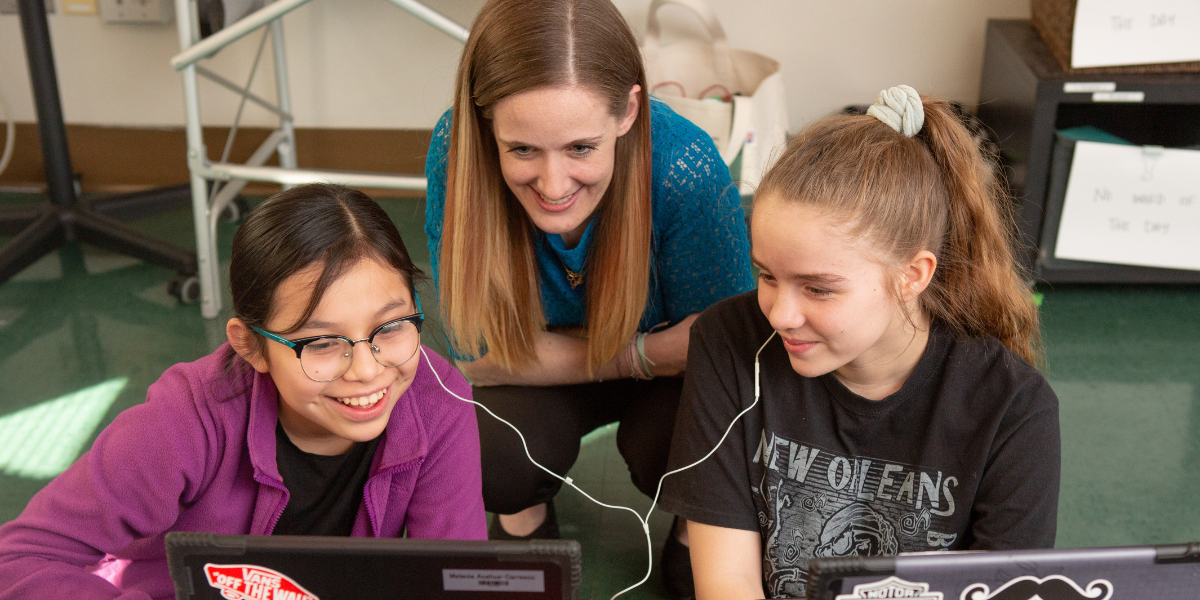 Woman helping two students.